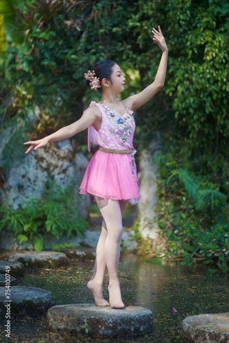 Beautiful girl ballerina dancing. Ballerina Project Show in the nature. A girl poses as a ballet performer in the green natural park. She was posting relax  and happiness.