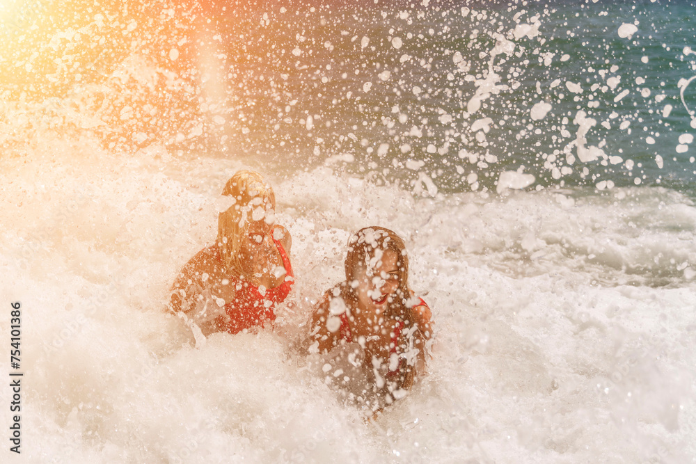 Obraz premium Women ocean play. Seaside, beach daytime, enjoying beach fun. Two women in red swimsuits enjoying themselves in the ocean waves.