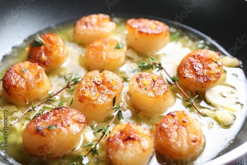 Delicious scallops with sauce in frying pan, closeup