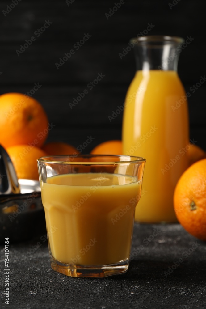 Tasty fresh oranges and juice on black table, closeup