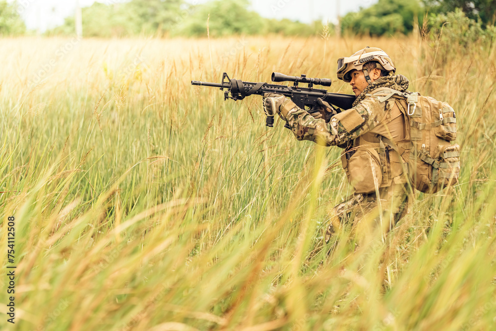 Fototapeta premium The captain of the military unit was in the grass. Prepare the M16 rifle. Send out your rifle and shoot enemies at range in the jungle battlefield. Wear camouflage clothing, a backpack, and sunglasses