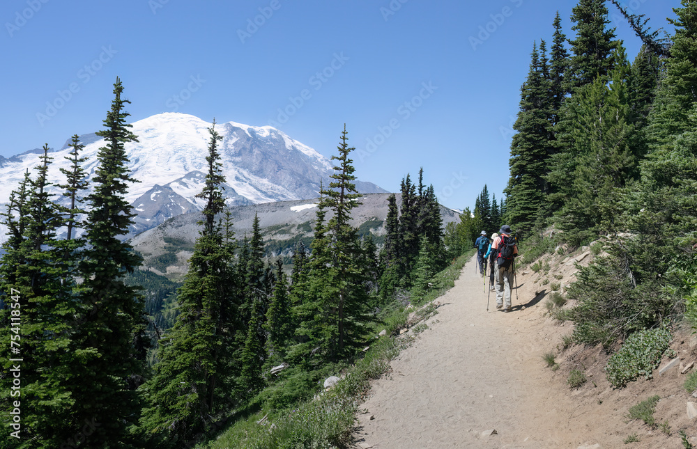 People hiking the Sunrise Trail at Mount Rainier National Park in summer. Mt Rainier in the background. Washington State.