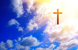 Cross on blue sky with clouds and sun. Christian religion concept.