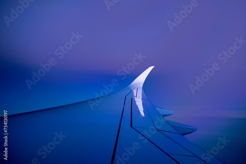 Wing of flying airplane on luxury blue and pink sunrise sky. 