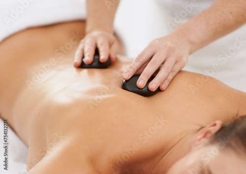 Relax, hot stone massage and woman with therapist at spa for health, wellness and luxury holistic treatment. Self care, peace and girl in natural body therapy, comfort or calm pamper service at hotel