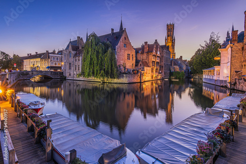 Rosary Quay in Bruges in the evening. View of the canal with historic buildings and famous belfry. Reflections of the old merchant houses on the water surface. Boats at the jetty