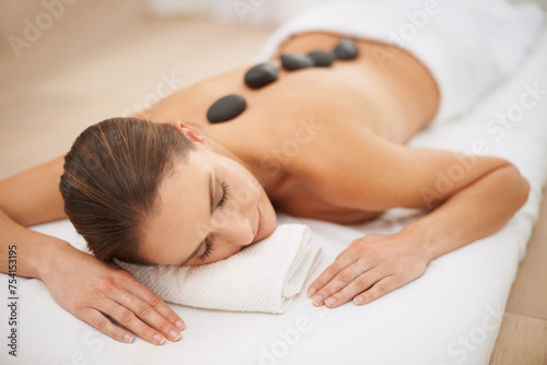 Relax, stone massage and woman at spa for health, zen wellness and luxury holistic treatment. Self care, peace and girl with natural body therapy, comfort and calm pamper service at hotel for detox