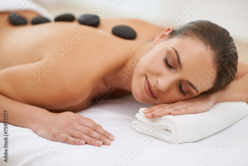 Relax, hot stone massage and woman on bed at spa for health, zen wellness and luxury holistic treatment. Self care, peace and girl on table for body therapy, comfort and calm pamper service at hotel