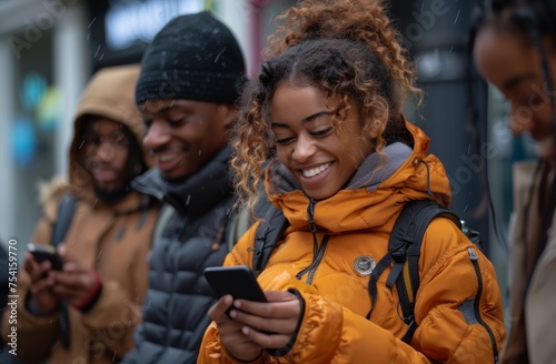 A group of young friends are laughing and playing with their smartphones together in the city, demonstrating a concept of social media sharing. Its composition includes different races and ages. They 