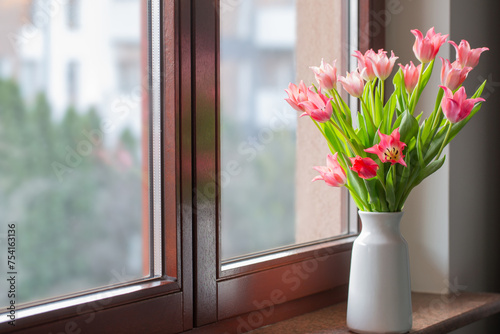 pink tulips in vase on windowsill