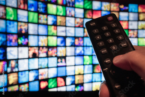 Man using remote control to watch a movie streaming service on TV. Video-on-demand subscription service and platform on television. Stream series, films and shows online.