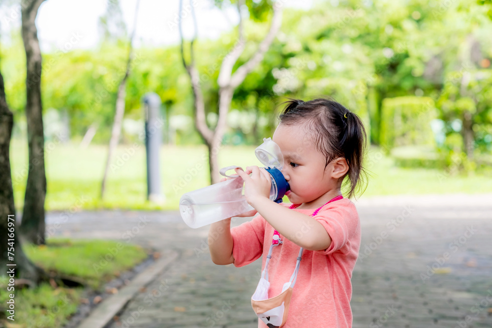 Little asian girl drinking water in garden park. Summer day. Copy space. Little asian girl drinking water in garden park. Summer day. Copy space.