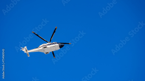 White helicopter on blue sky background, Close-up, selective focus, tinted image. Helicopter flight, delivery of passengers by air.