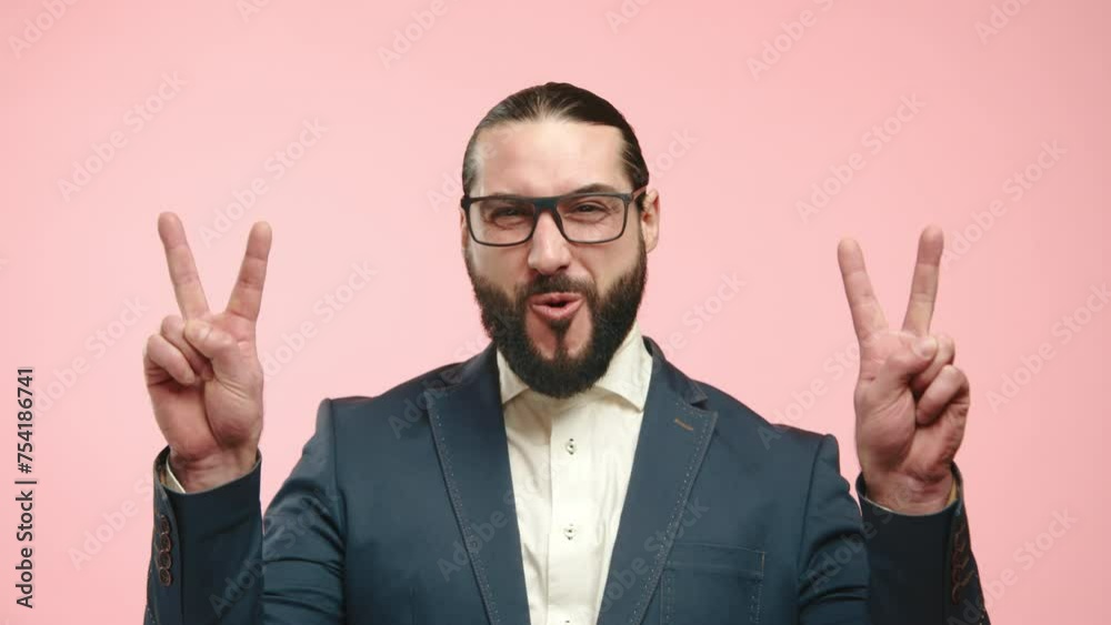Euphoric bearded man in business attire celebrating with a peace sign, his joy evident against a vibrant pink background. Camera 8K RAW. 