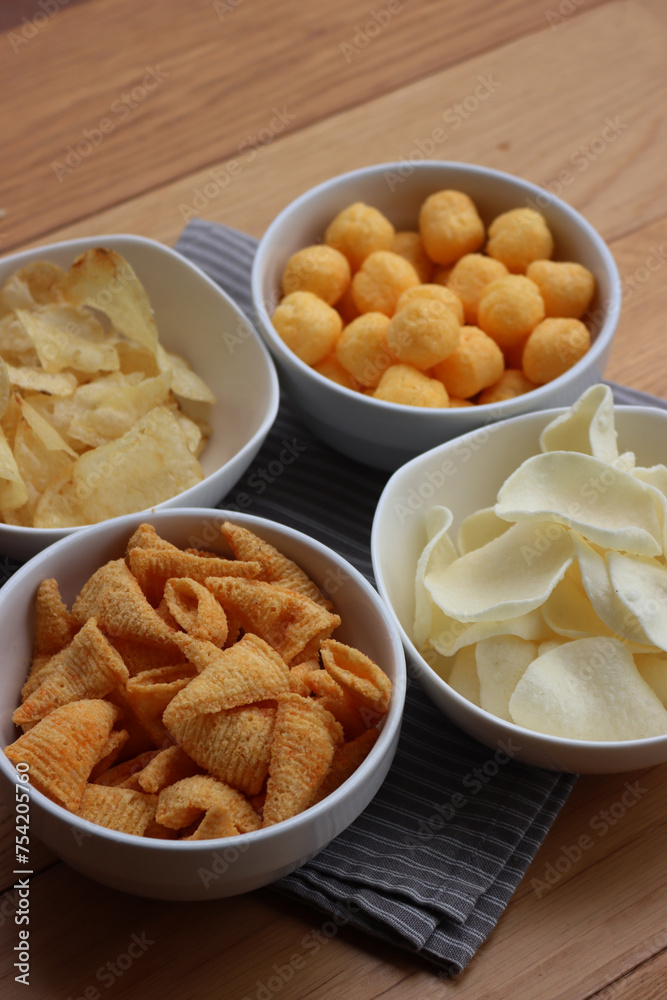Top view of white ceramic bowls with different kind of chips on wooden table Top view of white ceramic bowls with different kind of chips on wooden table