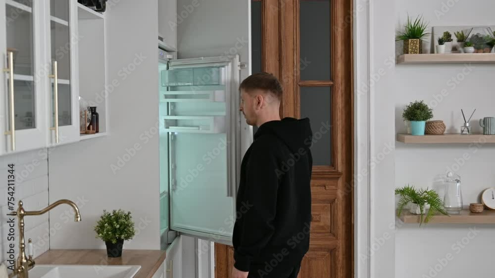 The young man opened the refrigerator to drink a glass of water. The athlete quenches his thirst after training. High quality 4k footage The young man opened the refrigerator to drink a glass of water. The athlete quenches his thirst after training. High quality 4k footage