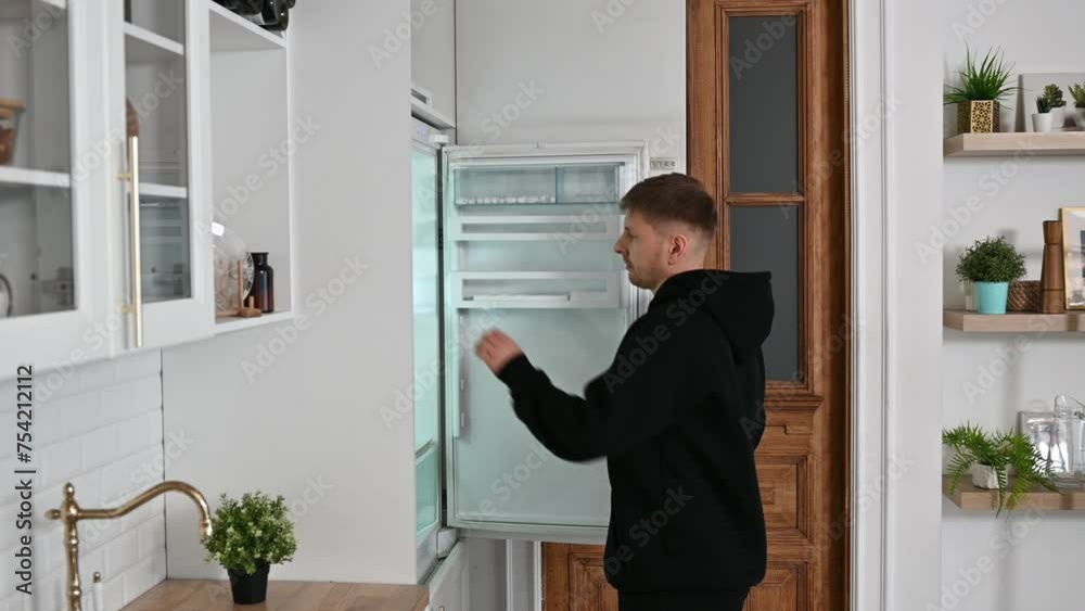 The young man opened the refrigerator to drink a glass of water. The athlete quenches his thirst after training. High quality 4k footage The young man opened the refrigerator to drink a glass of water. The athlete quenches his thirst after training. High quality 4k footage