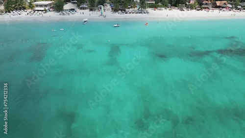 Aerial video above vacationing people and boats on jamaica coastline