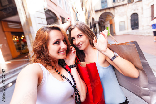 Two caucasian young women having fun in the city while shopping