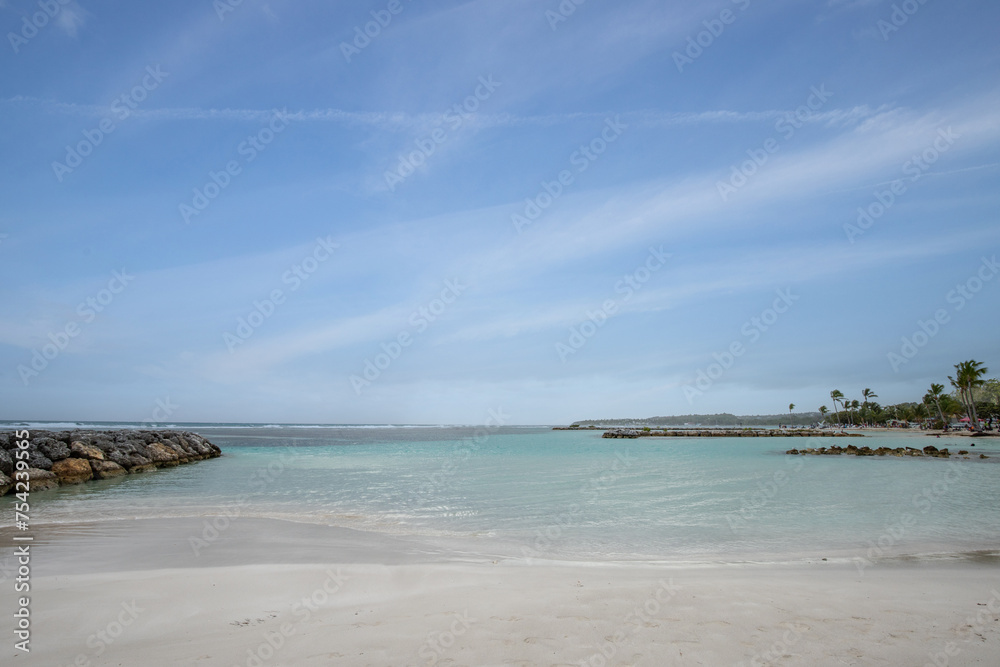 Romantic Caribbean sandy beach with palm trees, turquoise sea. Morning landscape shot at sunrise at Plage de Bois Jolan, Guadeloupe, French Antilles