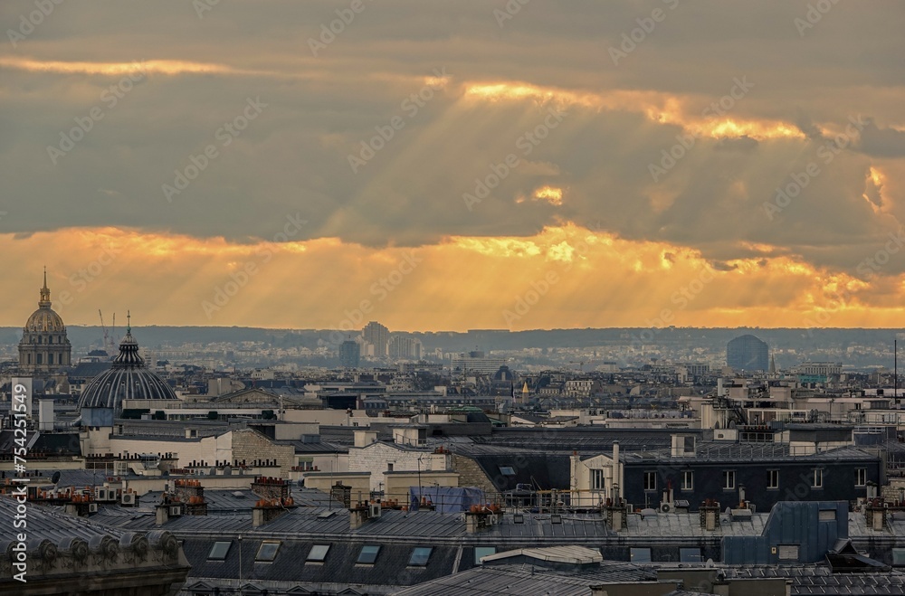 Vue panoramique sur le ciel de Paris en hauteur et rayons du soleil traversant les nuages, avec effet d'accentuation de lumière chaude	