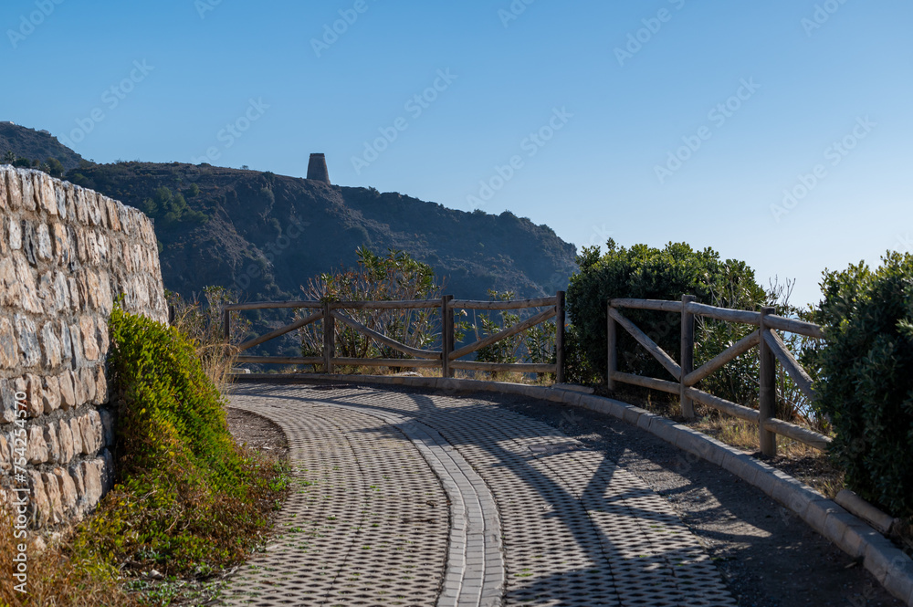 Fototapeta premium Pedestrian path next to the sea through the Mediterranean park that connects the beaches of Almuñécar (Granada, Spain)