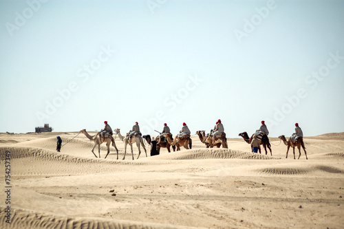 Tourists riding camel on Sahara Desert near Douz oasis in Kebili Governorate, Tunisia photo