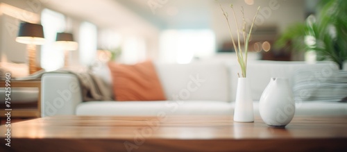 A table adorned with two decorative vases and a vibrant plant  set against a defocused living room background. The vases and plant add a touch of elegance and nature to the room.