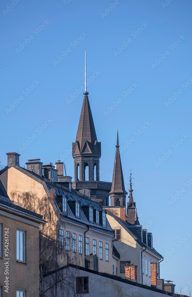 Facades tin roof with dorms, chimneys and towers in the district Mariaberget, a sunny winter day in Stockholm