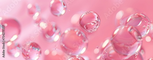 A pink background with transparent gel droplets floating. Abstract background with clear serum or gel drops. Flat lay of hydro alcoholic gel splashes