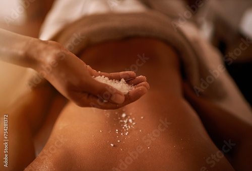 Hand, back and salt at spa for massage, skin care and wellness for luxury, holistic therapy and peace. Grain, exfoliate and health for lifestyle, body and person on table, calm and natural photo
