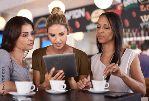 Woman, together and read at coffee shop with tablet for online menu or restaurant review, diversity and relax for leisure. Female friends, digital technology and internet to search or browse website.