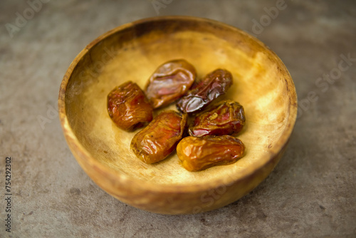 Dried dates fruits in wooden bowl isolated, ramadhan fruits.