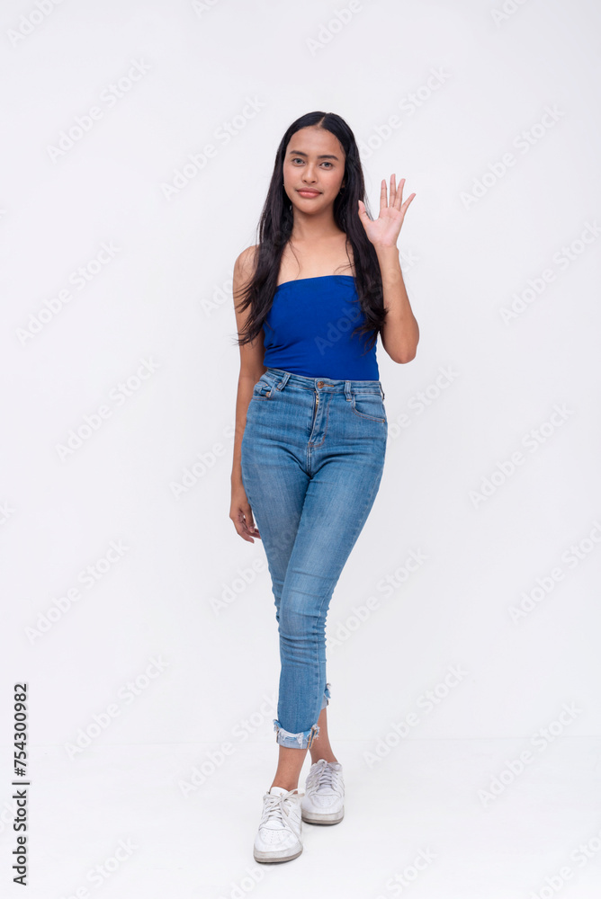 Full-length photo of a personable Asian woman waving greeting with a friendly smile, isolated on a white background. Full-length photo of a personable Asian woman waving greeting with a friendly smile, isolated on a white background.