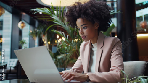 Professional woman works intently on a laptop in a modern cafe.