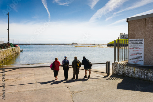 Four daytrippers look out to sea. Seahouses harbour, Northumberland. Horizontal format with room for copy. photo