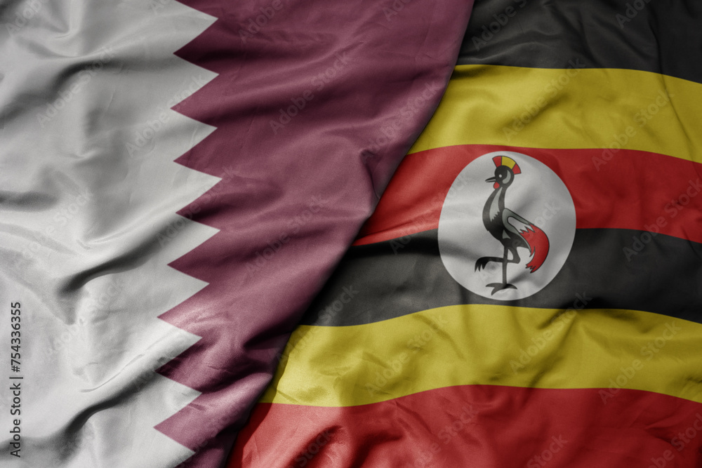 Fototapeta premium big waving national colorful flag of uganda and national flag of qatar.