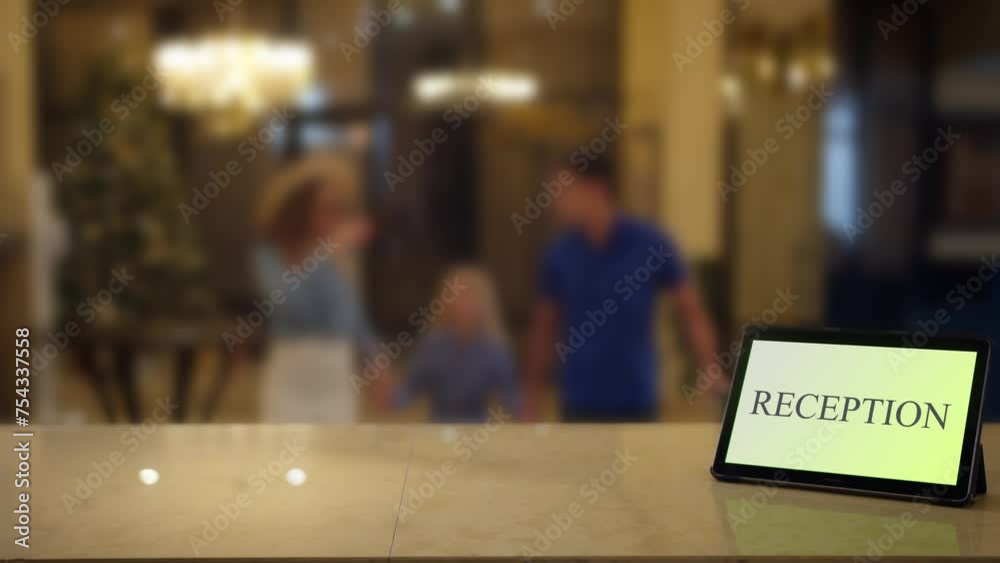A family on holiday in a hotel approaches to the reception desk with a tablet labeled reception A family on holiday in a hotel approaches to the reception desk with a tablet labeled reception