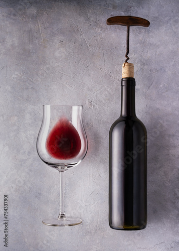 Still life. glass and bottle of wine to uncork. Textured background.