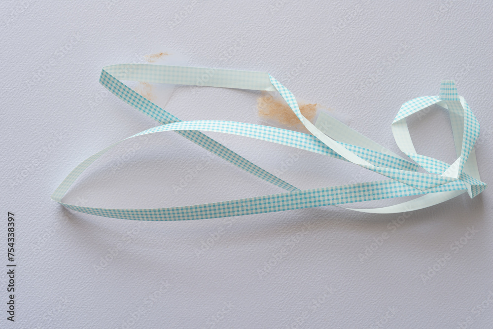 length of crumpled used ribbon with blue plaid pattern on textured paper - obrazy, fototapety, plakaty 