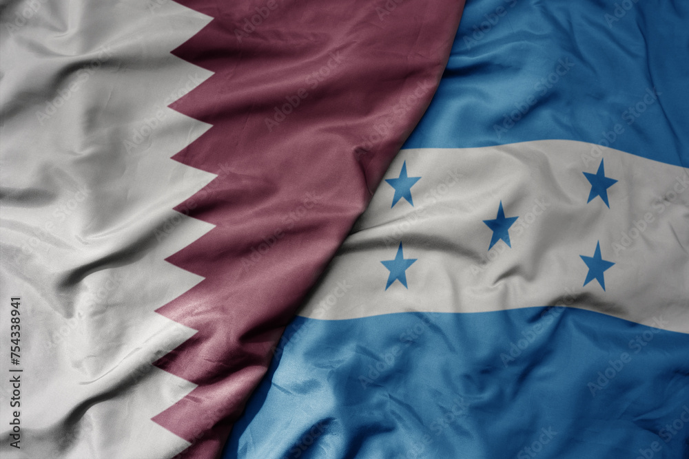 big waving national colorful flag of honduras and national flag of qatar. big waving national colorful flag of honduras and national flag of qatar.