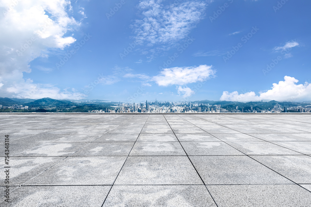 Empty square floor and mountains with city skyline
