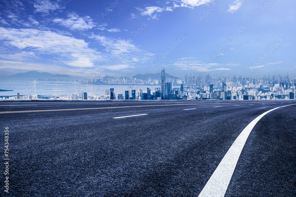 Empty asphalt road and mountains with city skyline Empty asphalt road and mountains with city skyline