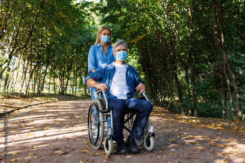 Support and Strength: Woman Wearing Mask Helps Man in Wheelchair