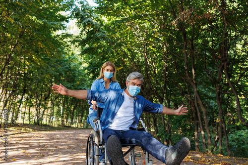 Inclusive Outdoor Moments: Woman Guides Man in Wheelchair with Masks © Andrii 