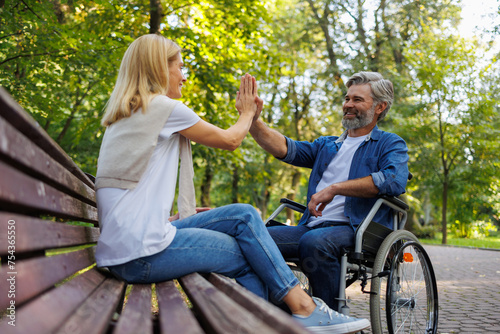 Celebrating Inclusivity: Woman High-Fives Man in Wheelchair © Andrii 