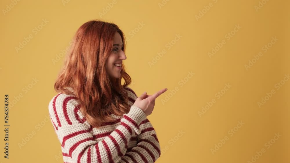 Girl pointing fingers to show mockup space on yellow background in studio Girl pointing fingers to show mockup space on yellow background in studio