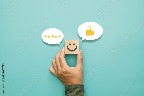 Service rating, satisfaction and positive feedback concept. Customer show smile face emoticon on a wooden cube with a like thumb up and icon fivestar in a speech bubble photo