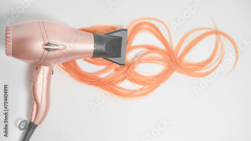 A piece of wavy peach fuzz hair with hair dryer on the white background.