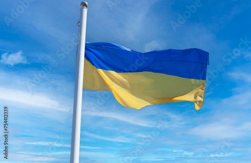 Ukrainian flag on a flagpole against a blue sky.